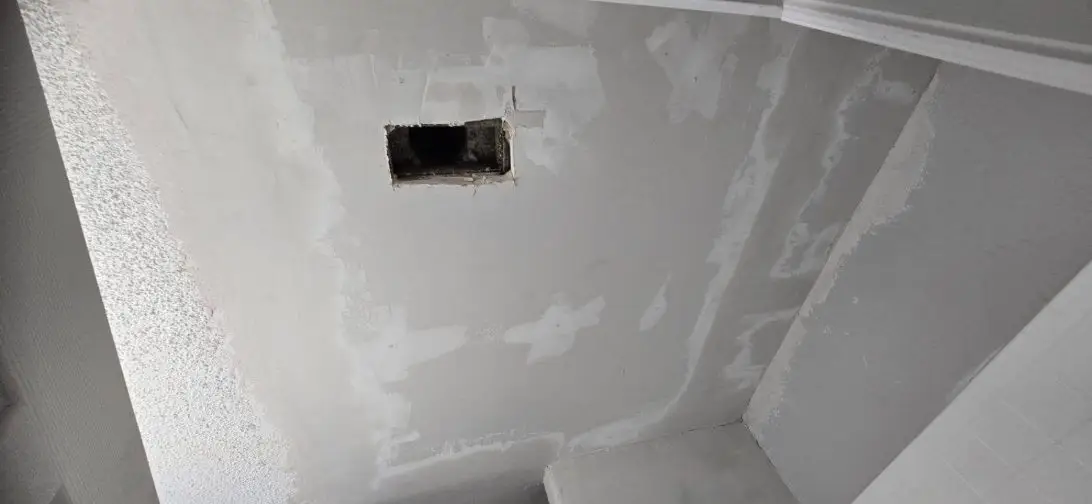 Ceiling with drywall patches mudded around a vent opening.