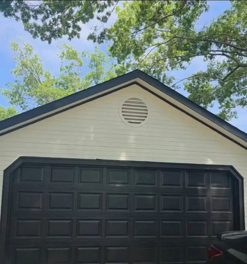 Detached garage repainted cream with black trim and a black garage door.