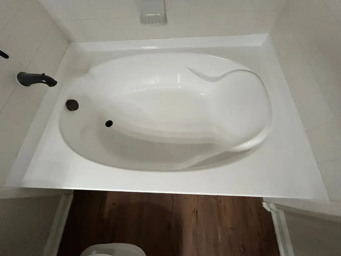 Garden tub resurfaced in glossy white, with dark fixtures.