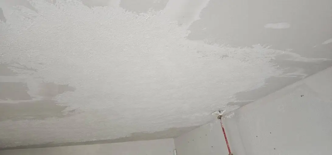 New drywall on the ceiling with fresh texture sprayed over the patches.